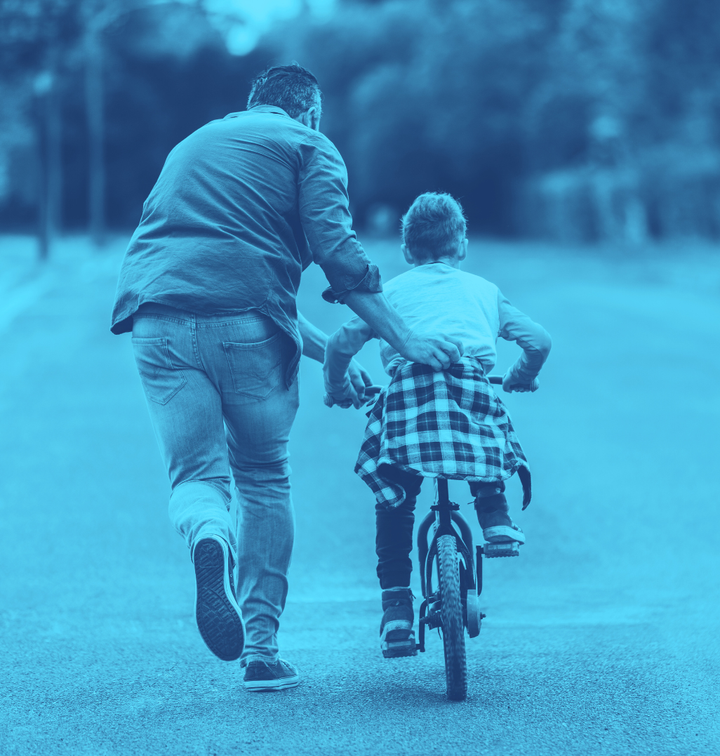 Man teaching son how to ride his bike.